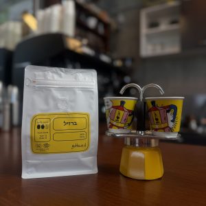 קפה ברזיל בשקית עם כוסות קפה צבעוניות על דלפק קפה.